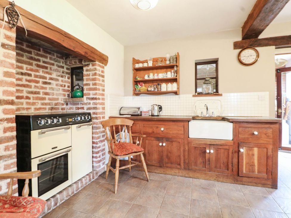 A kitchen with a stove, sink, and wooden shelves at The Barn in Tamworth