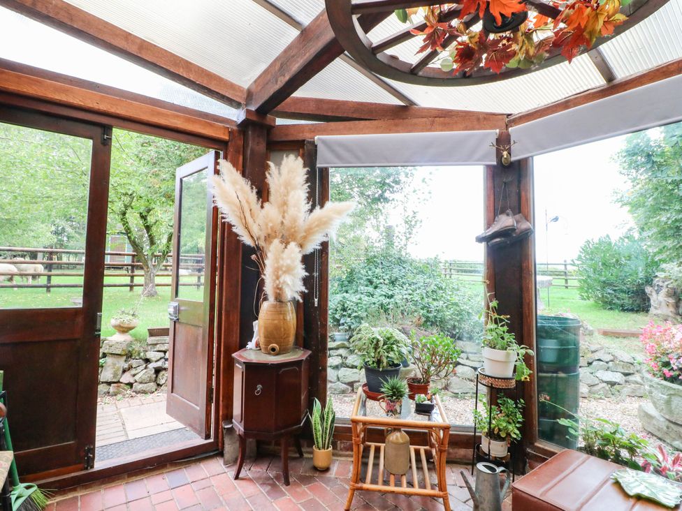 A conservatory with plants and an open door at The Barn in Tamworth