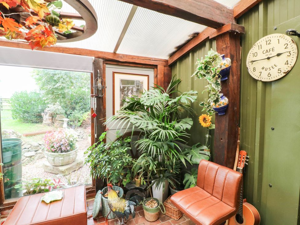 A conservatory with plants and seating at The Barn in Tamworth