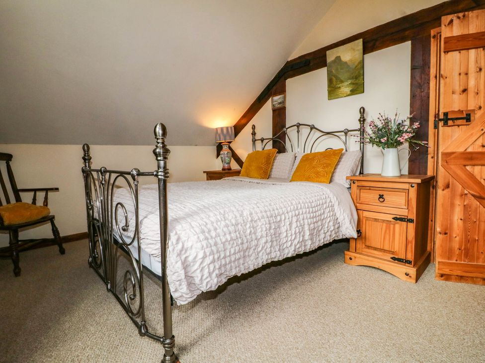 A bedroom with a bed, nightstand, and lamp at The Barn in Tamworth