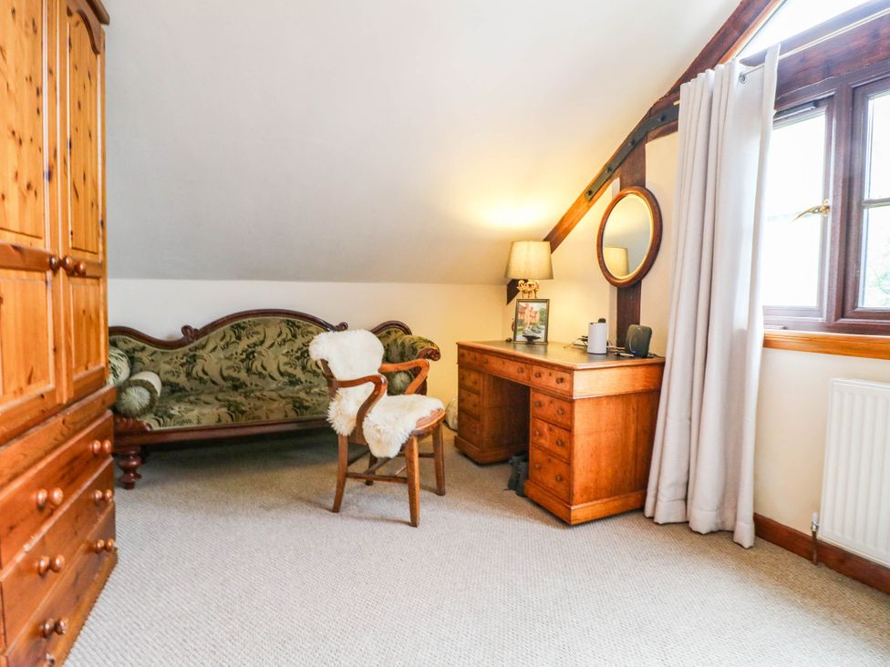 A bedroom with a wardrobe, desk, chair, and sofa at The Barn in Tamworth