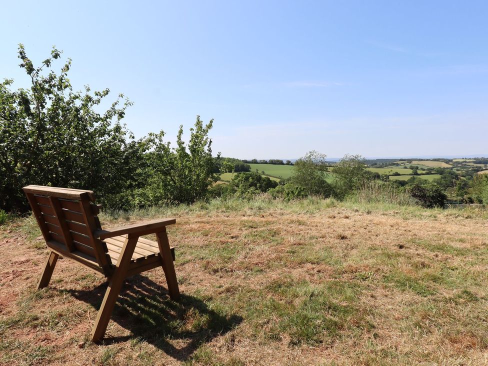 A bench with a view of fields and trees at Nelli Lodge at Mile End Crediton