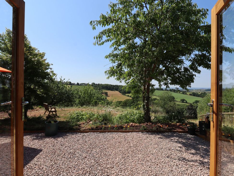 A view from a garden with a chair and tree at Nelli Lodge at Mile End, Crediton