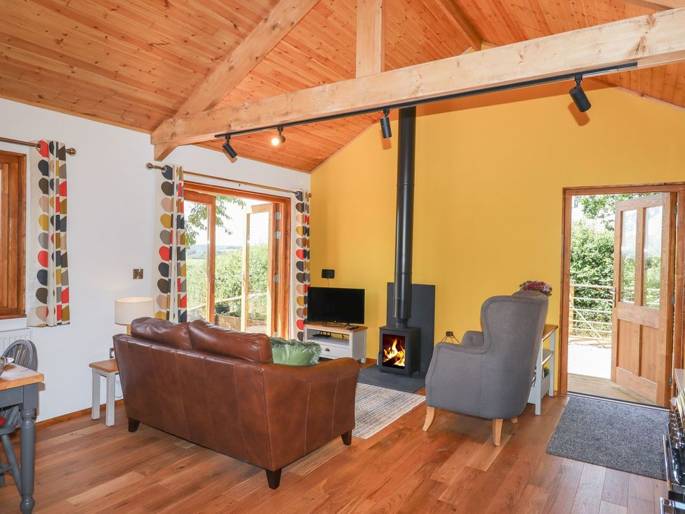 A living room with a fireplace and sofa at Nelli Lodge at Mile End, Crediton