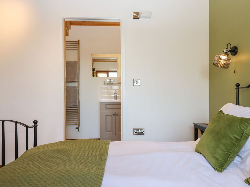 A bedroom with a bed and an ensuite bathroom at Nelli Lodge at Mile End Crediton