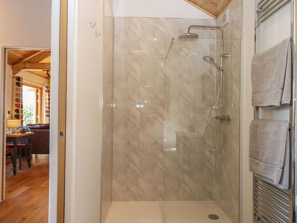 A bathroom with a shower and towel rack at Nelli Lodge at Mile End in Crediton