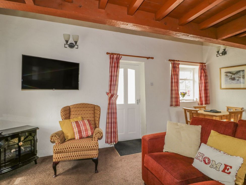 A living room with a television and an armchair at Cottage 1 in Braithwaite
