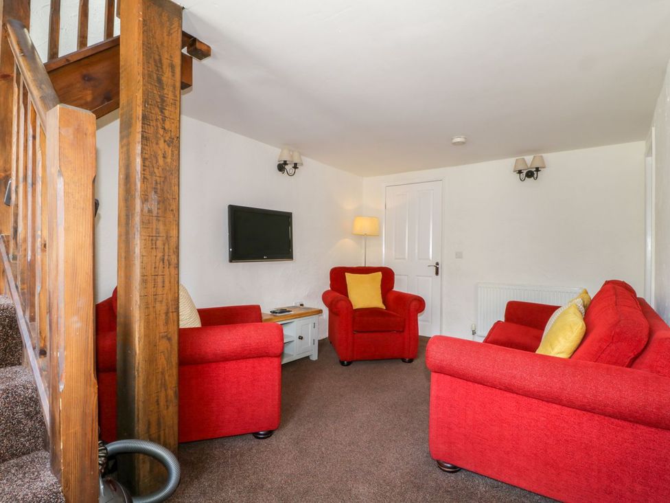 A living room with red furniture and a television at Cottage 2 in Keswick