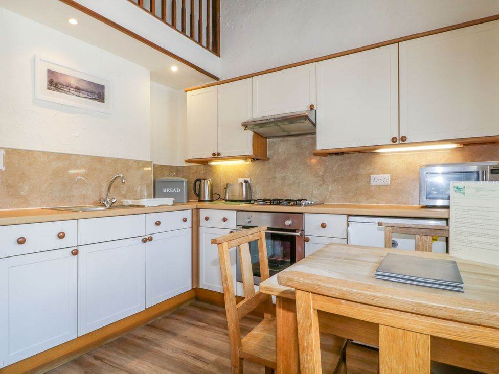A kitchen with cabinets, oven, and table at Cottage 2 in Keswick