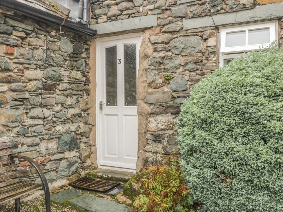 An entrance with a white door and stone wall at Cottage 3 in Keswick