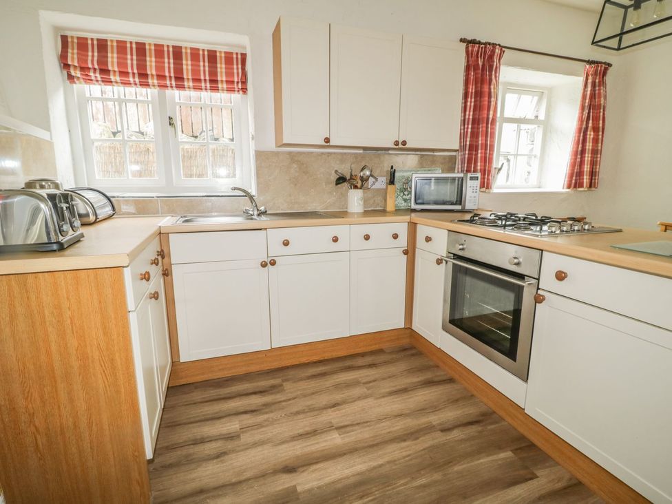 A kitchen with a sink, stove, and microwave at Cottage 3 in Keswick