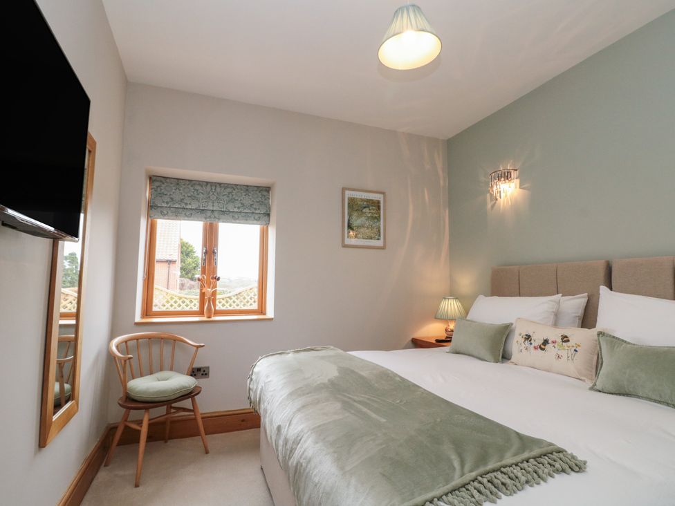 A bedroom with a bed and television at Bumble Bee Lodge in Filey