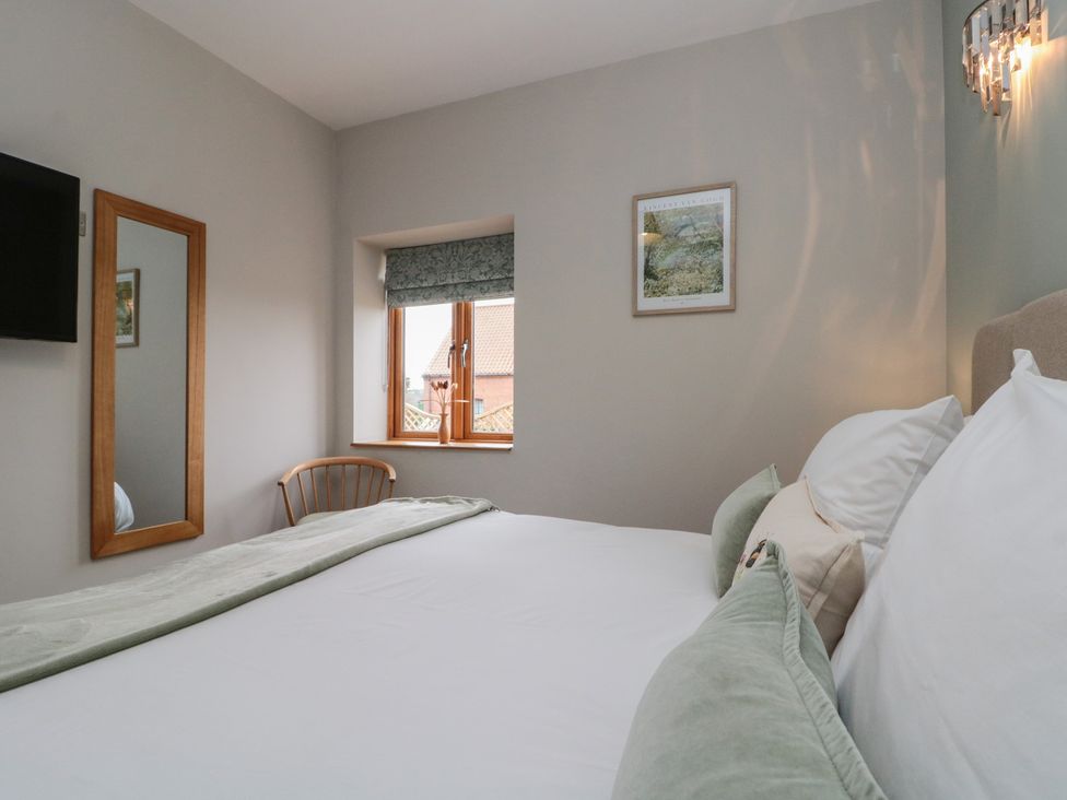 A bedroom with a bed, mirror and television at Bumble Bee Lodge in Filey