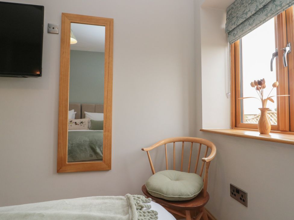 A bedroom with a television, mirror, and chair at Bumble Bee Lodge in Filey