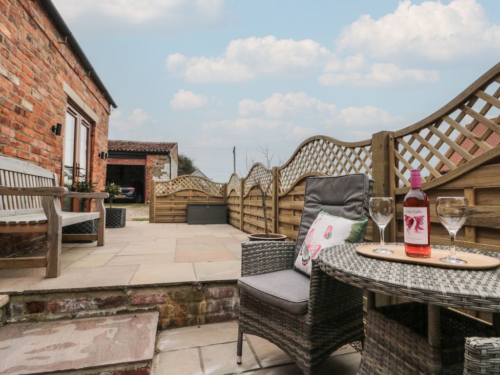 A patio with chairs and a table featuring wine glasses at Bumble Bee Lodge in Filey