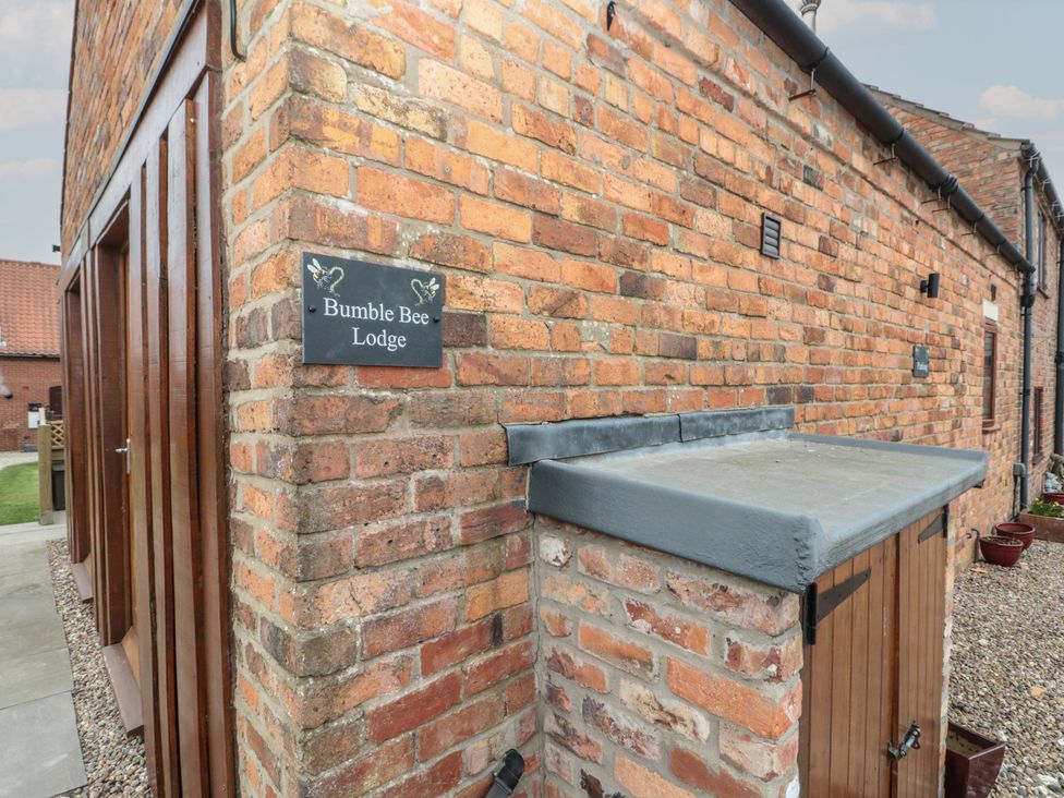 An exterior view of Bumble Bee Lodge in Filey with a brick wall and storage unit