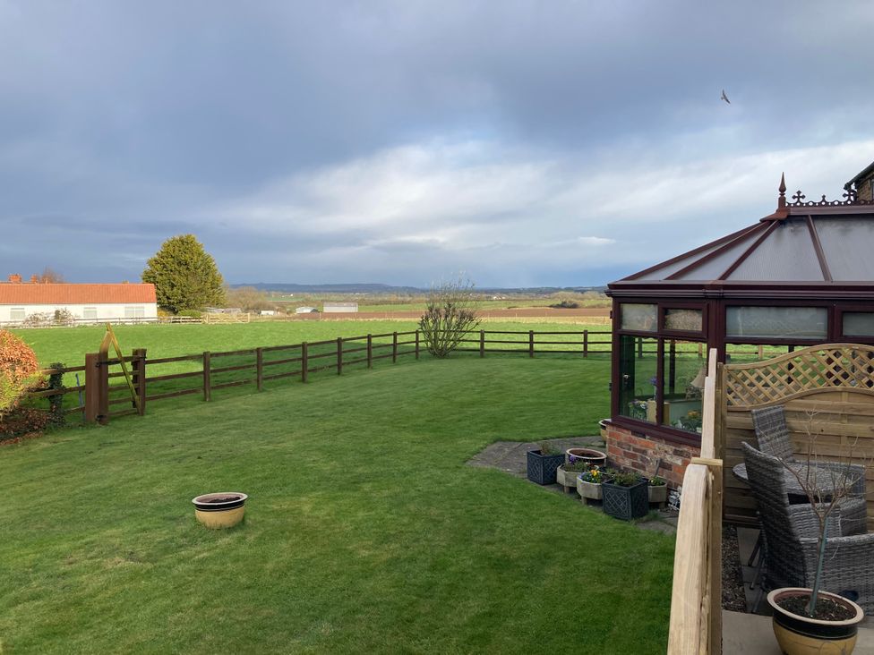 A garden with a conservatory and grass at Bumble Bee Lodge in Muston