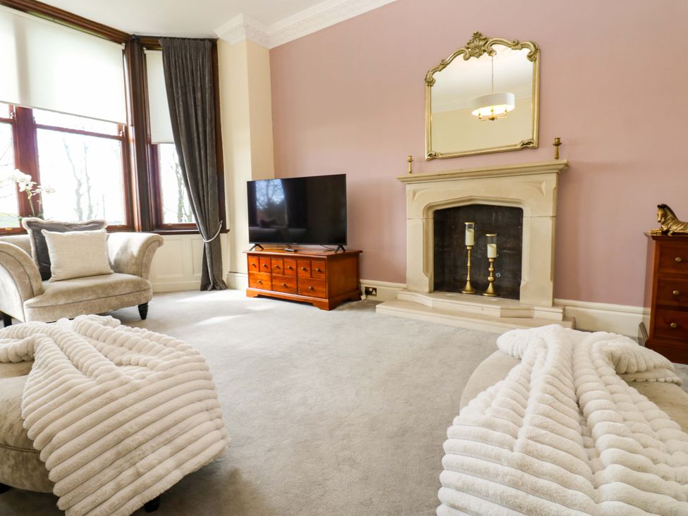 A living room with a sofa, television, and fireplace at Flaxstead Grange in Newbottle