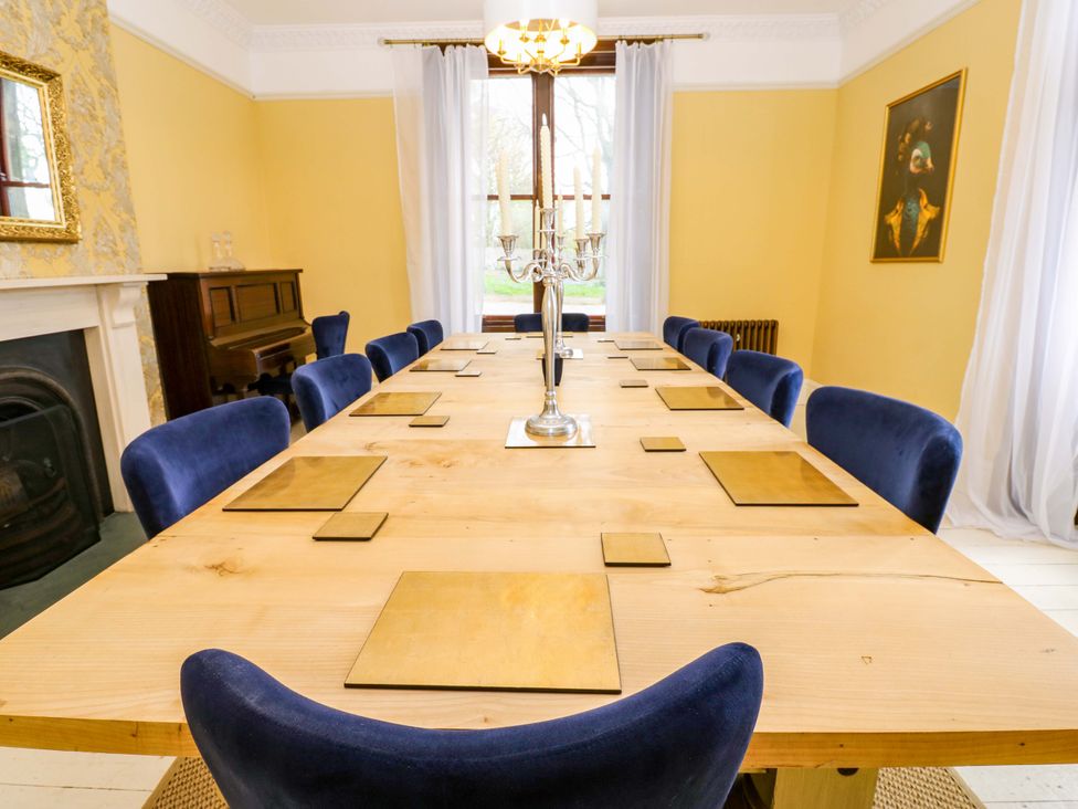 A dining room with a long table and blue chairs at Flaxstead Grange in Newbottle