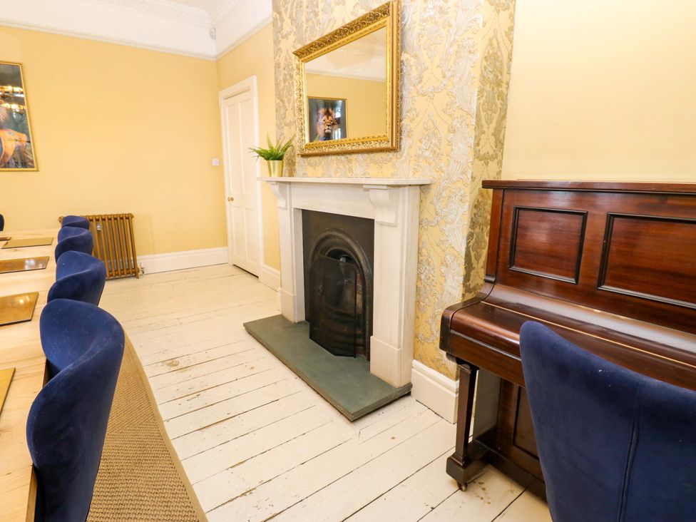 A dining room with a fireplace and piano at Flaxstead Grange in Newbottle