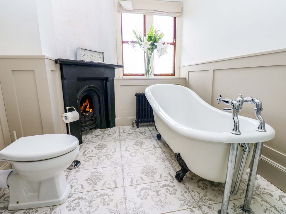 A bathroom with a bathtub, toilet, and fireplace at Flaxstead Grange in Newbottle