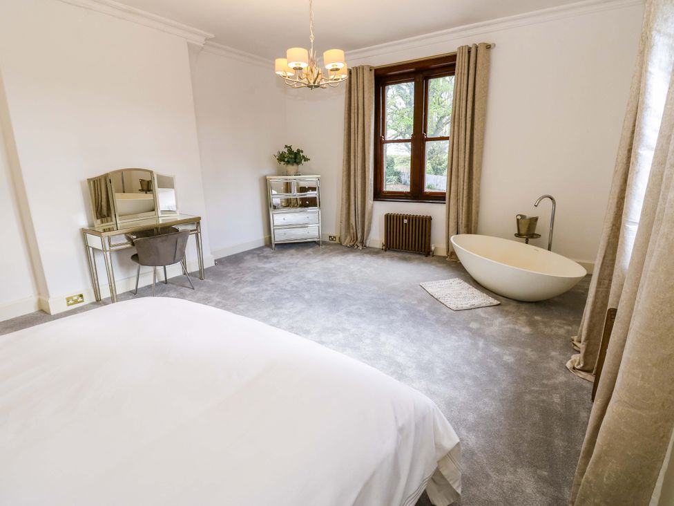 A bedroom with a bathtub and vanity table at Flaxstead Grange in Newbottle