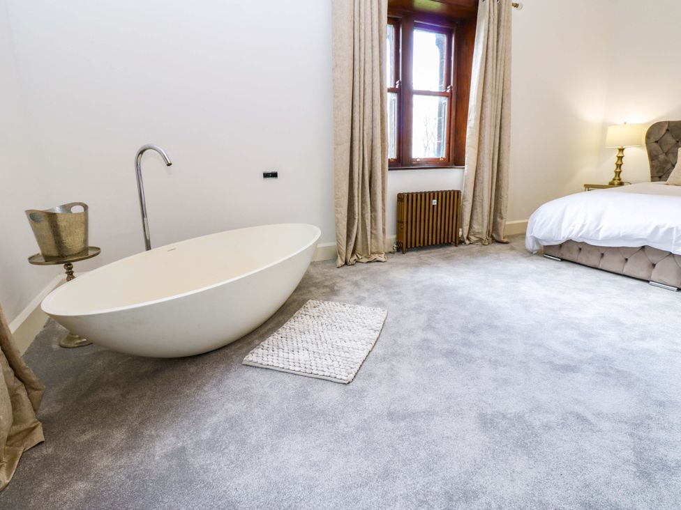 A bedroom with a bathtub and bed at Flaxstead Grange in Newbottle