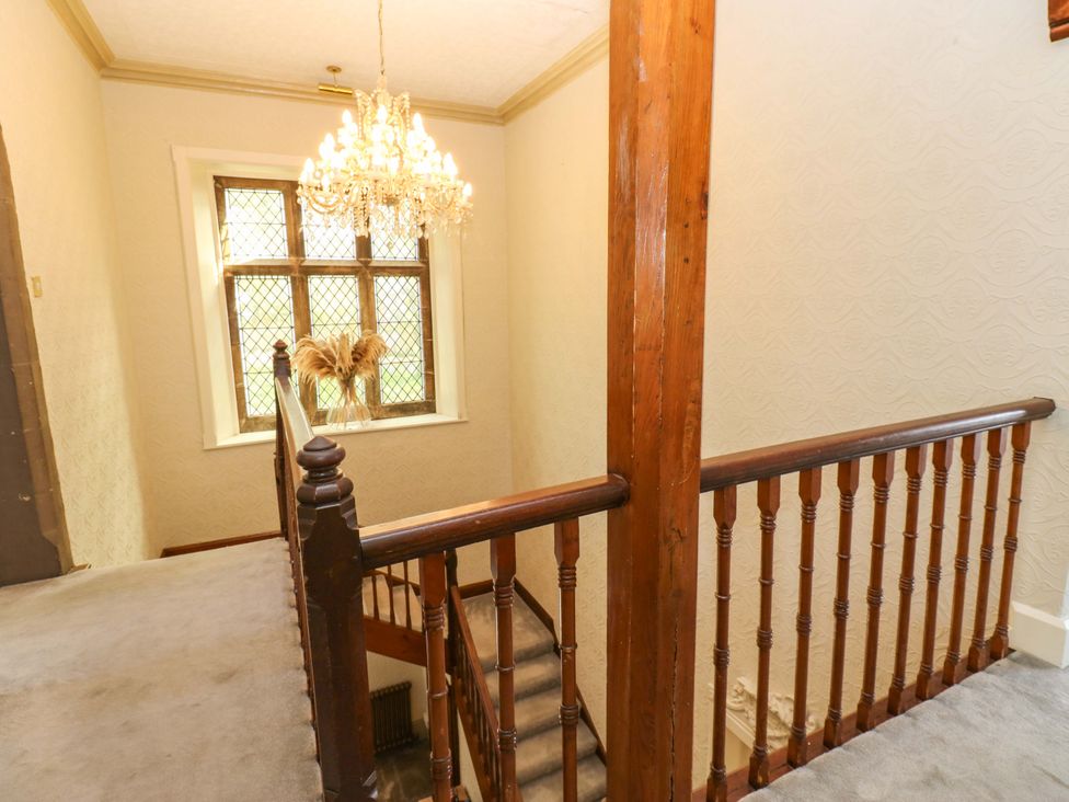 A hallway with a staircase and chandelier at Flaxstead Grange in Newbottle