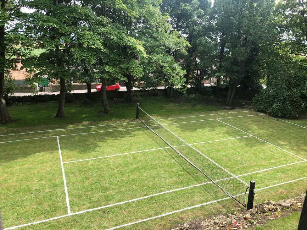 A tennis court with a net and trees surrounding at Flaxstead Grange in Newbottle