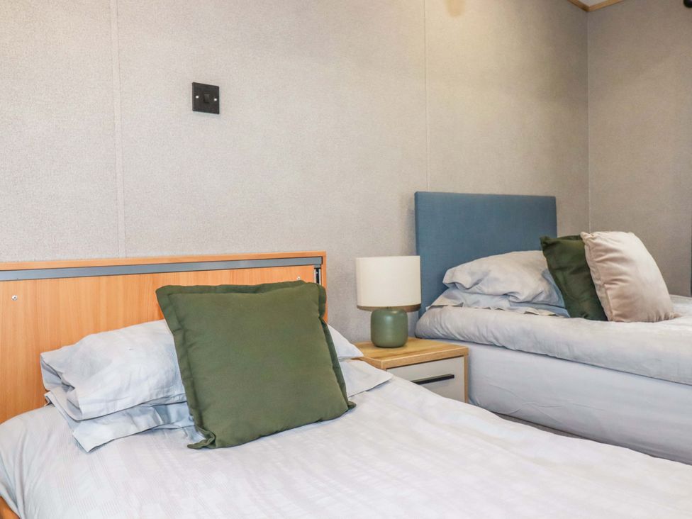 A bedroom with two beds and a lamp on a nightstand at Derwent L4 in Par