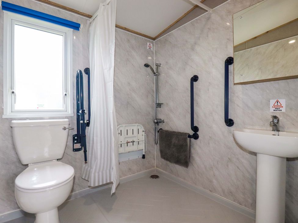A bathroom with a toilet, sink, shower and grab bars at Derwent L4 in Par