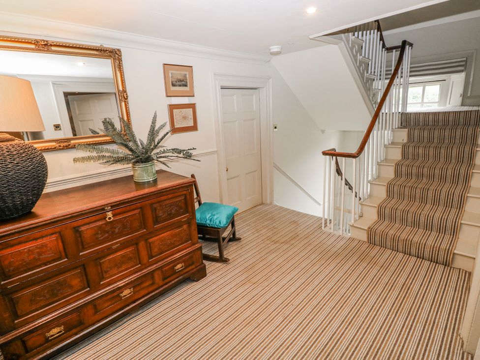 A hallway with a chest of drawers and a staircase at The Old Vicarage in Carmarthen