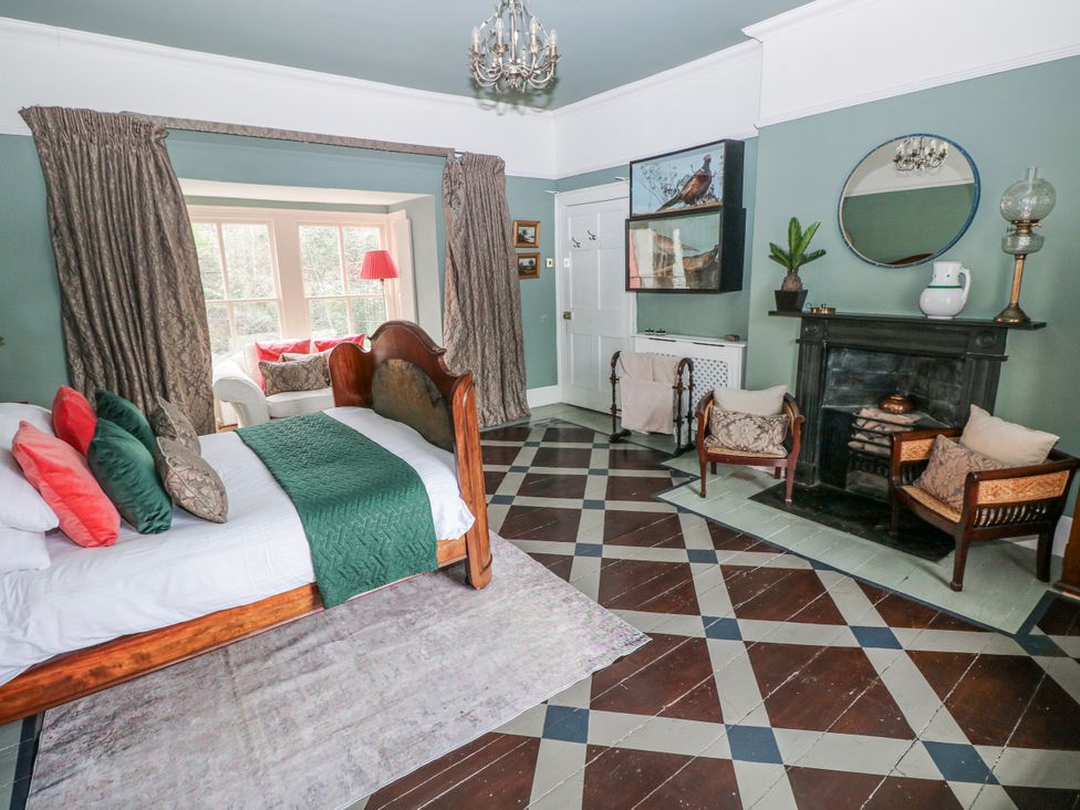 A bedroom with a bed and chairs at The Old Vicarage in Carmarthen