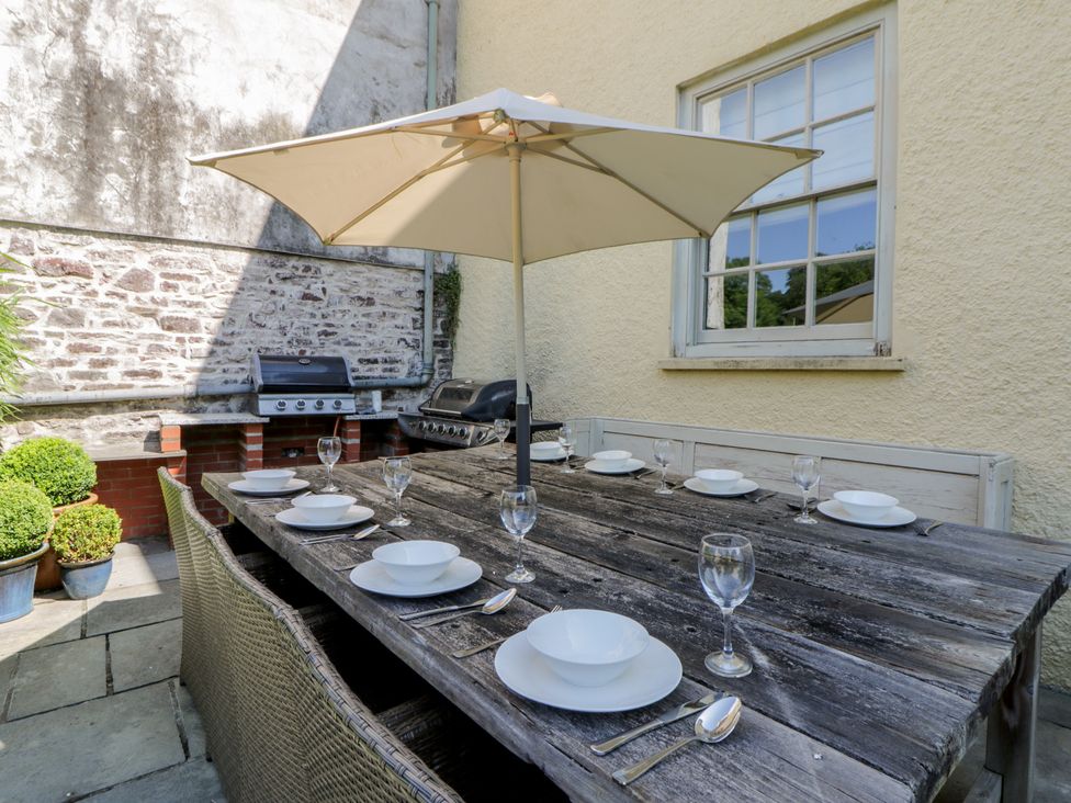 An outdoor dining area with a table and grill at The Old Vicarage in Laugharne