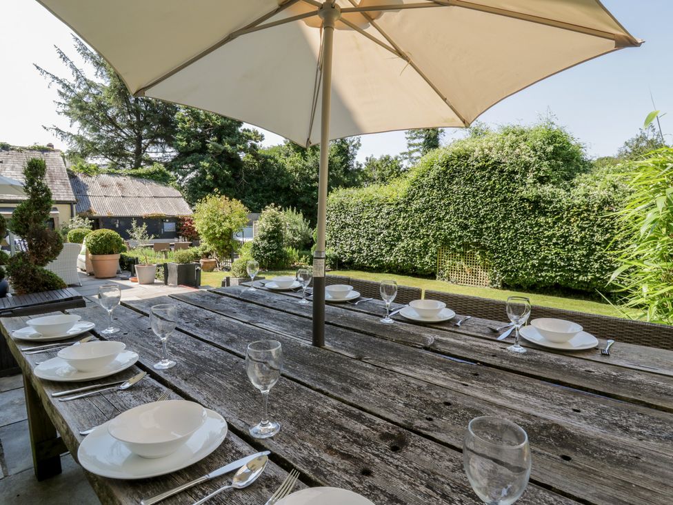 An outdoor dining area with a large table set for a meal at The Old Vicarage in Laugharne