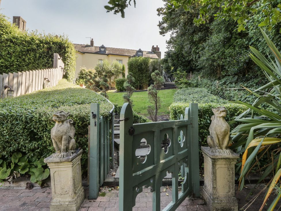 A garden with stone statues and a gate at The Old Vicarage in Laugharne