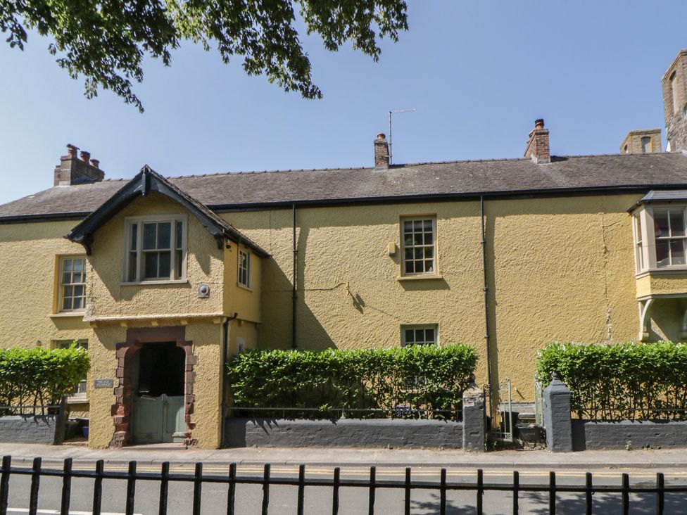 A yellow house with windows and a door surrounded by a hedge at The Old Vicarage in Laugharne