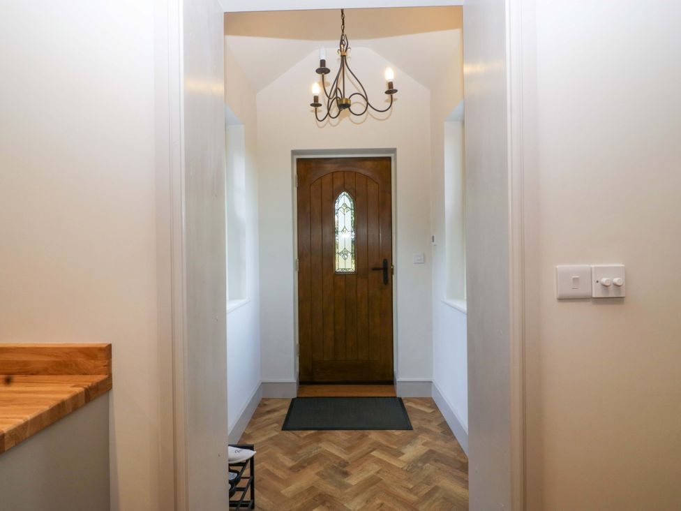 A hallway with a wooden door and chandelier at Broadmoor Chapel in Hereford