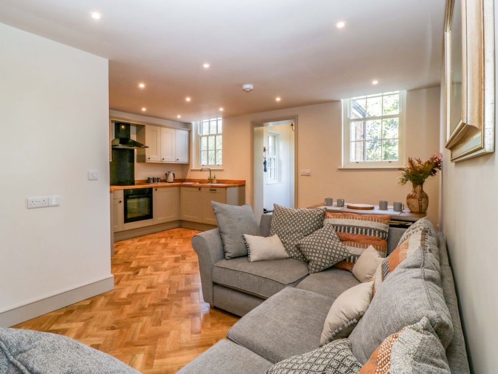 A living room with a sofa and a kitchen area at Broadmoor Chapel in Hereford