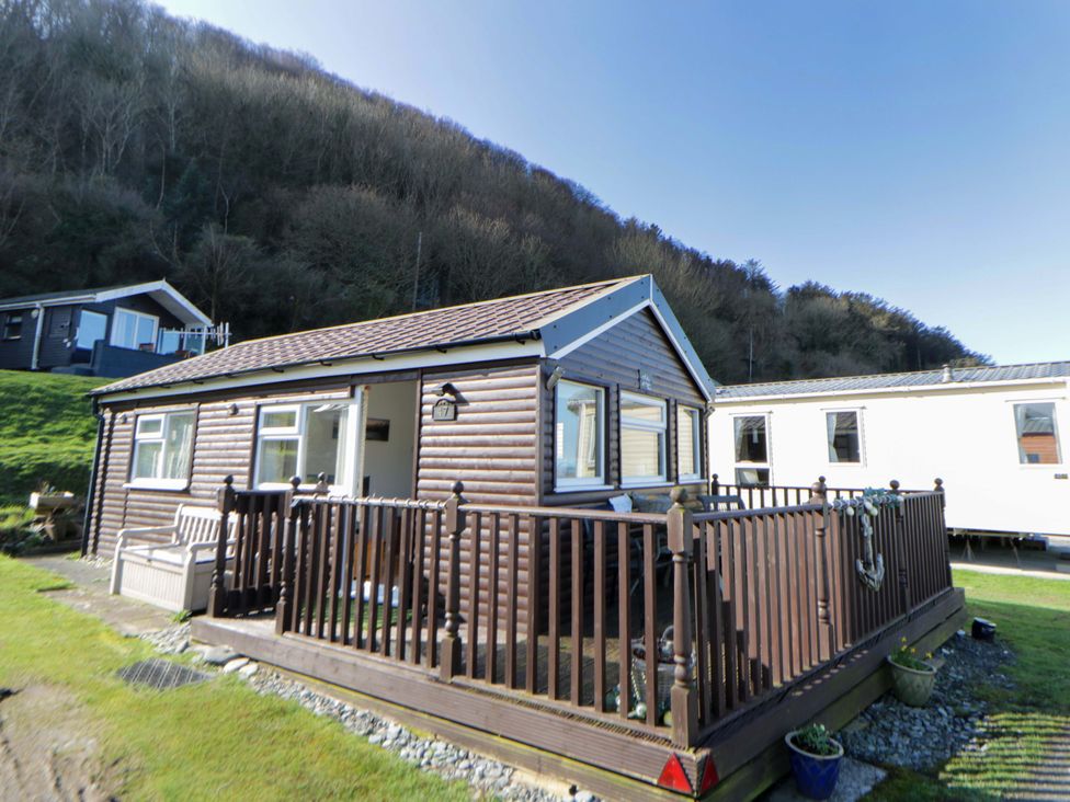 A house with a deck and railing at The Cosy Den in Clarach near Aberystwyth