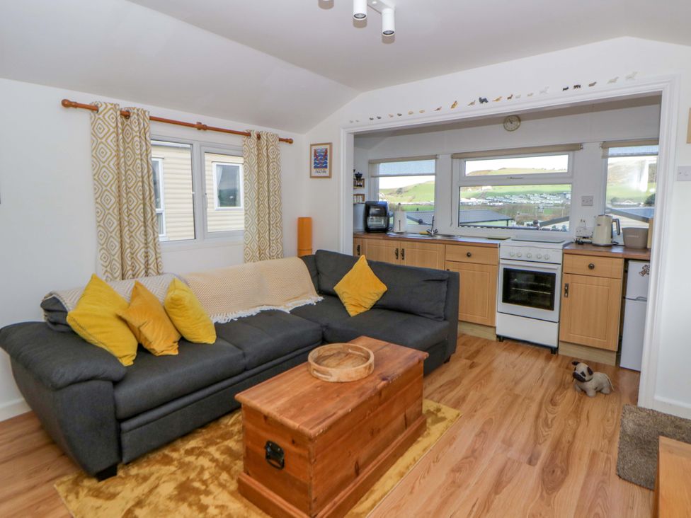 A living room with a sofa and kitchen area at The Cosy Den in Clarach near Aberystwyth