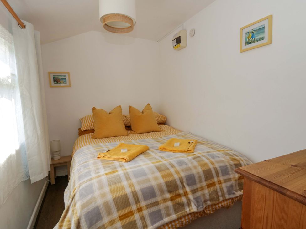 A bedroom with a bed and cushions at The Cosy Den in Clarach near Aberystwyth