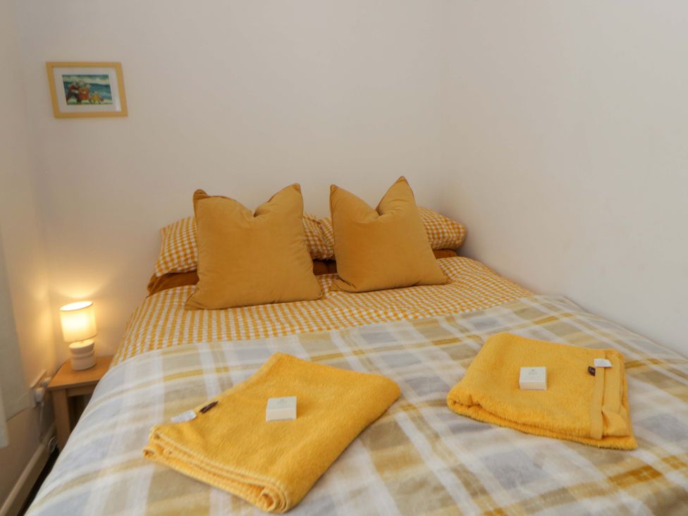 A bedroom with a bed and towels at The Cosy Den in Clarach near Aberystwyth