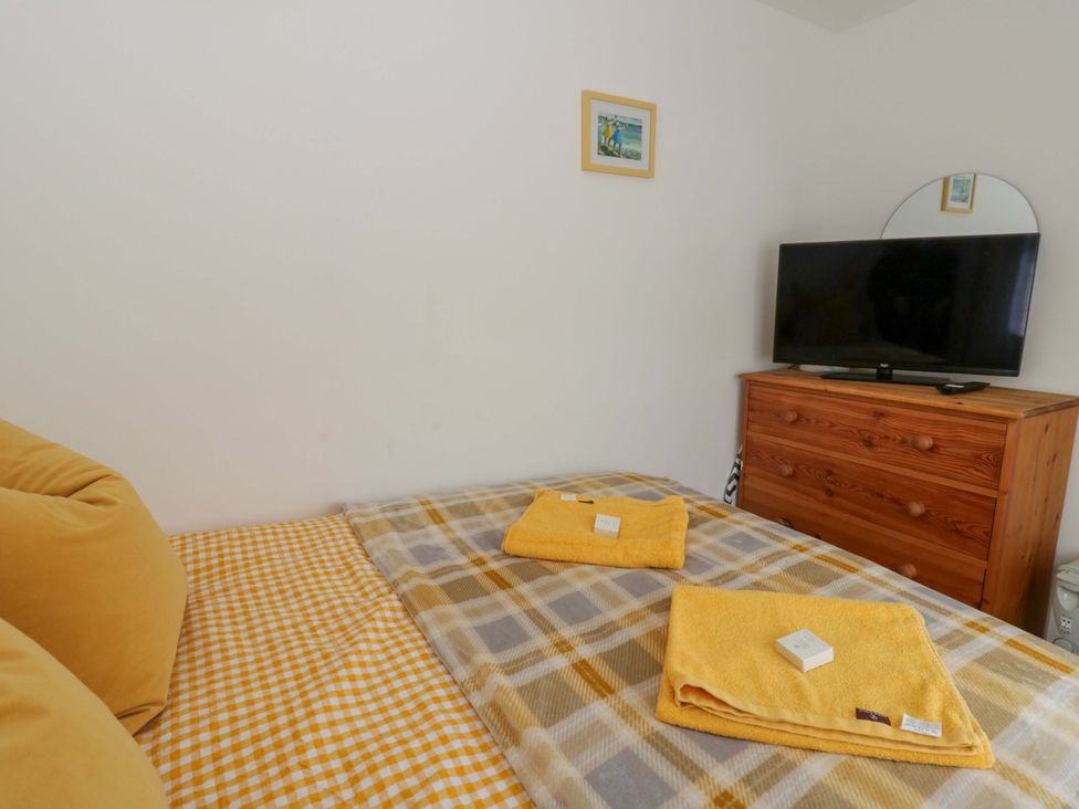 A bedroom with a bed and a television at The Cosy Den in Clarach near Aberystwyth