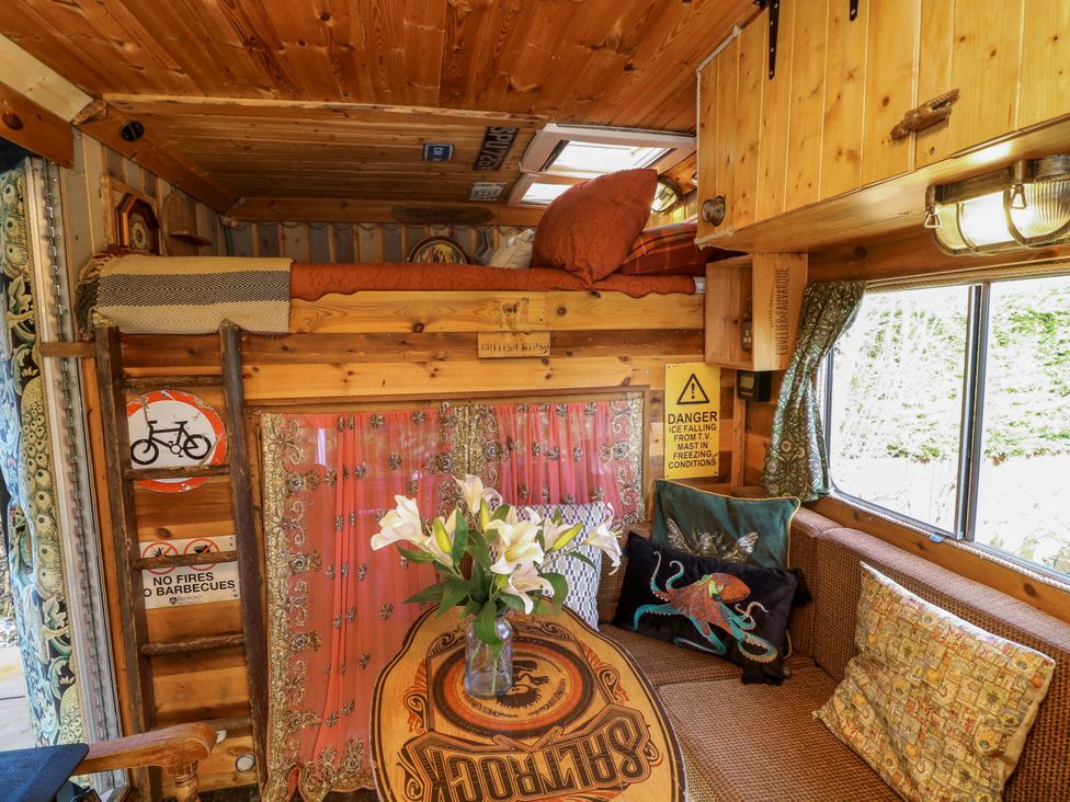 A living room with a loft bed and a table with flowers at Old Rosie in Grantham