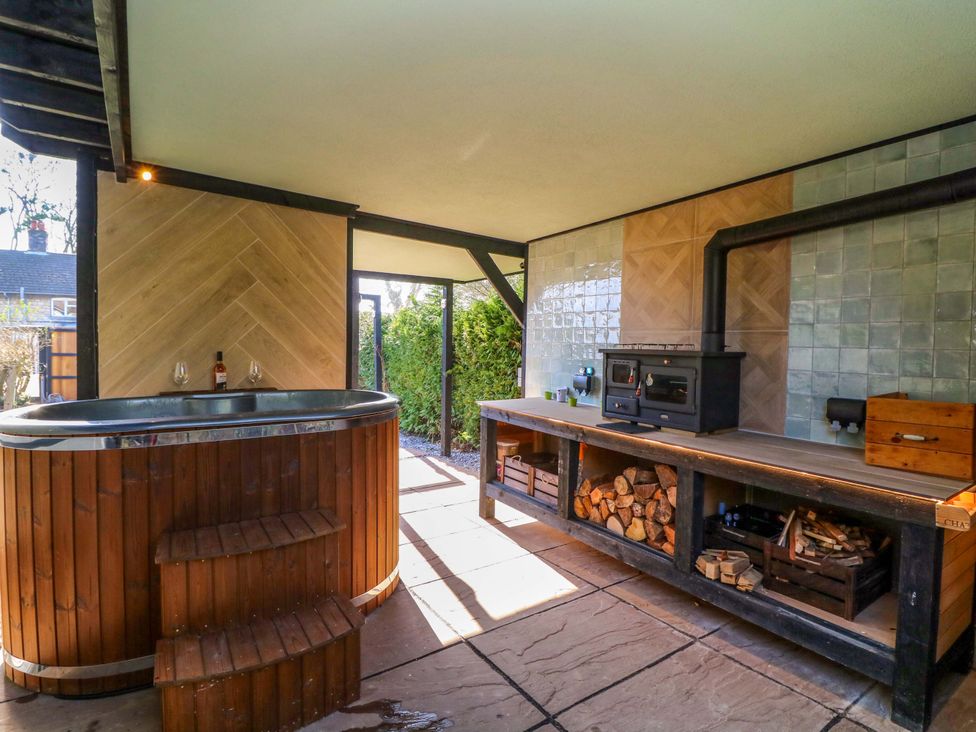 An outdoor kitchen with a hot tub and barbecue at Old Rosie in Grantham
