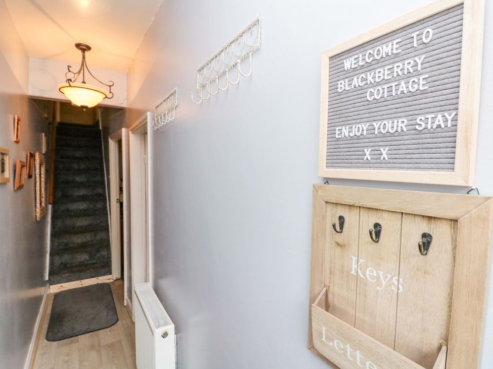 A hallway with a staircase and key holder at Blackberry Cottage in Bridlington