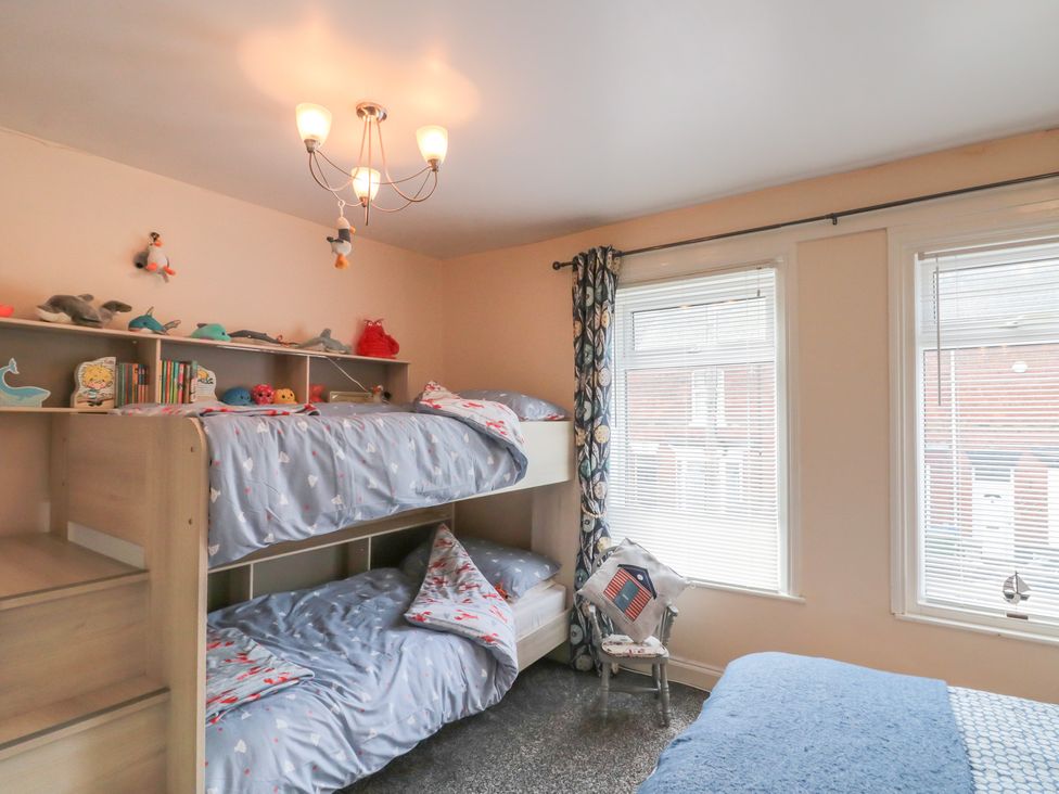 A bedroom with a bunk bed and bookshelf at Blackberry Cottage in Bridlington