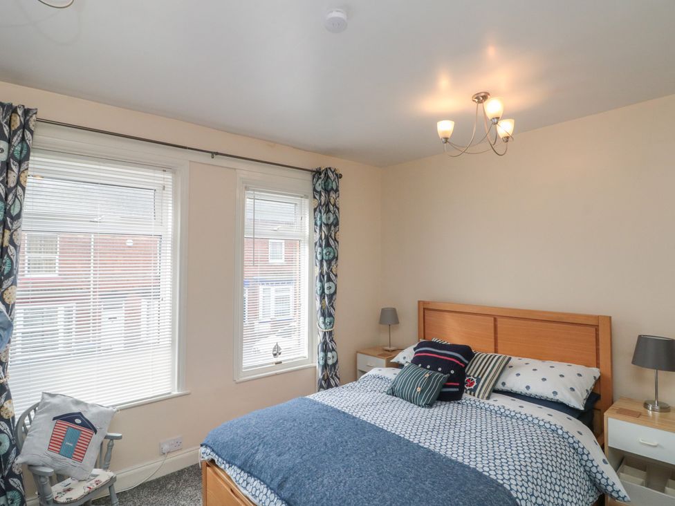 A bedroom with a bed and windows at Blackberry Cottage Bridlington