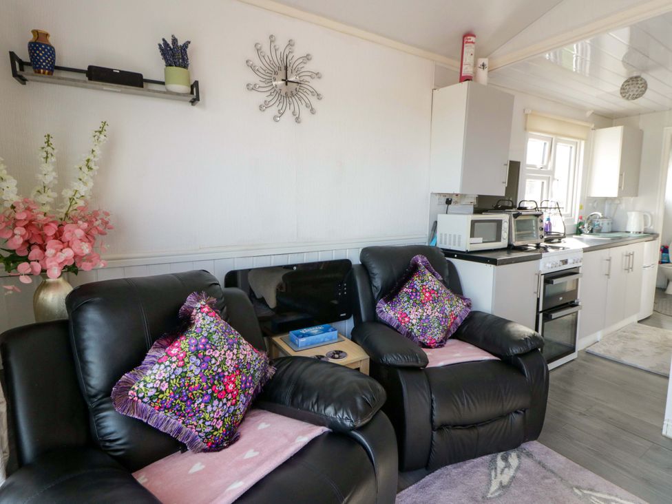 A living room with two armchairs and kitchen area at The Comfort Den near Aberystwyth